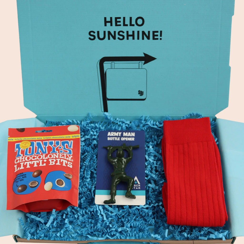 turquoise gift box with the words hello sunshine on containing Tonys chocolate, an army man bottle opener and red socks. The packaging is plastic free with turquoise tissue with turquoise paper shred