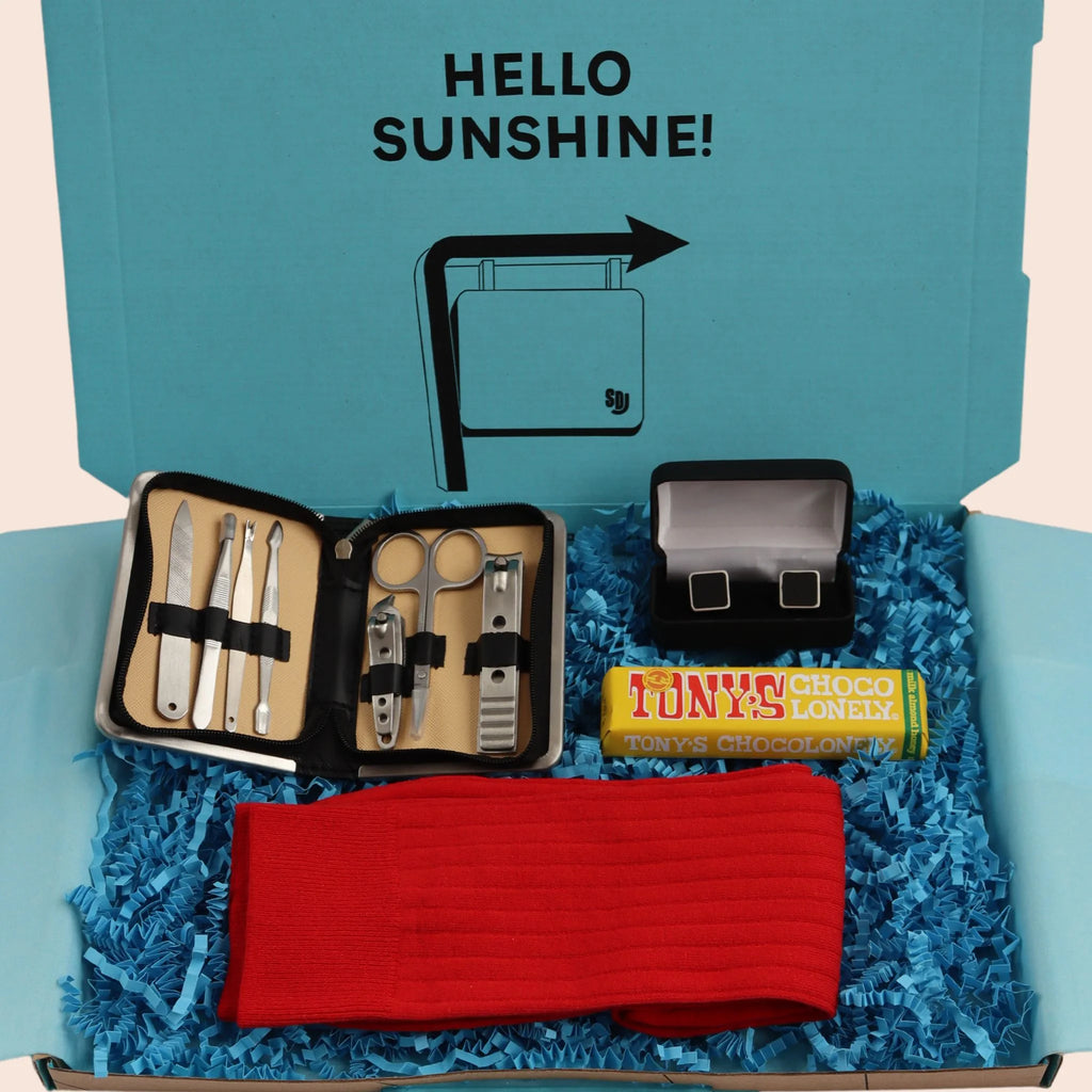 turquoise gift box with the words hello sunshine. The box contains Tonys chocolate, manicure set, black cube cufflinks in a box, and red socks. The packaging is plastic free with turquoise tissue with turquoise paper shred