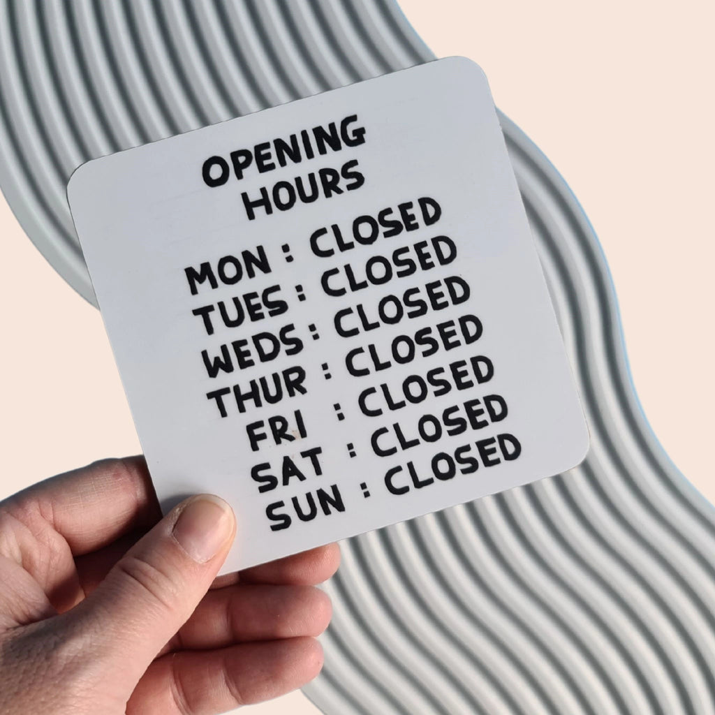 David Shrigley cork backed coaster with illustration of opening hours Mon to Sun closed