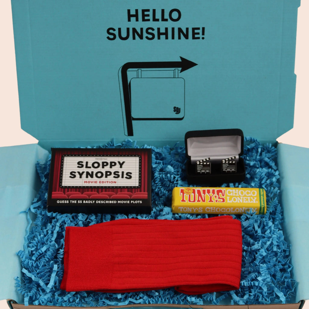 turquoise gift box with the words hello sunshine. The box contains Tonys chocolate, sloppy synopsis a movie themed game, directors clapperboard  cufflinks,  and red socks. The gifts are wrapped plastic free turquoise tissue with turquoise paper shred