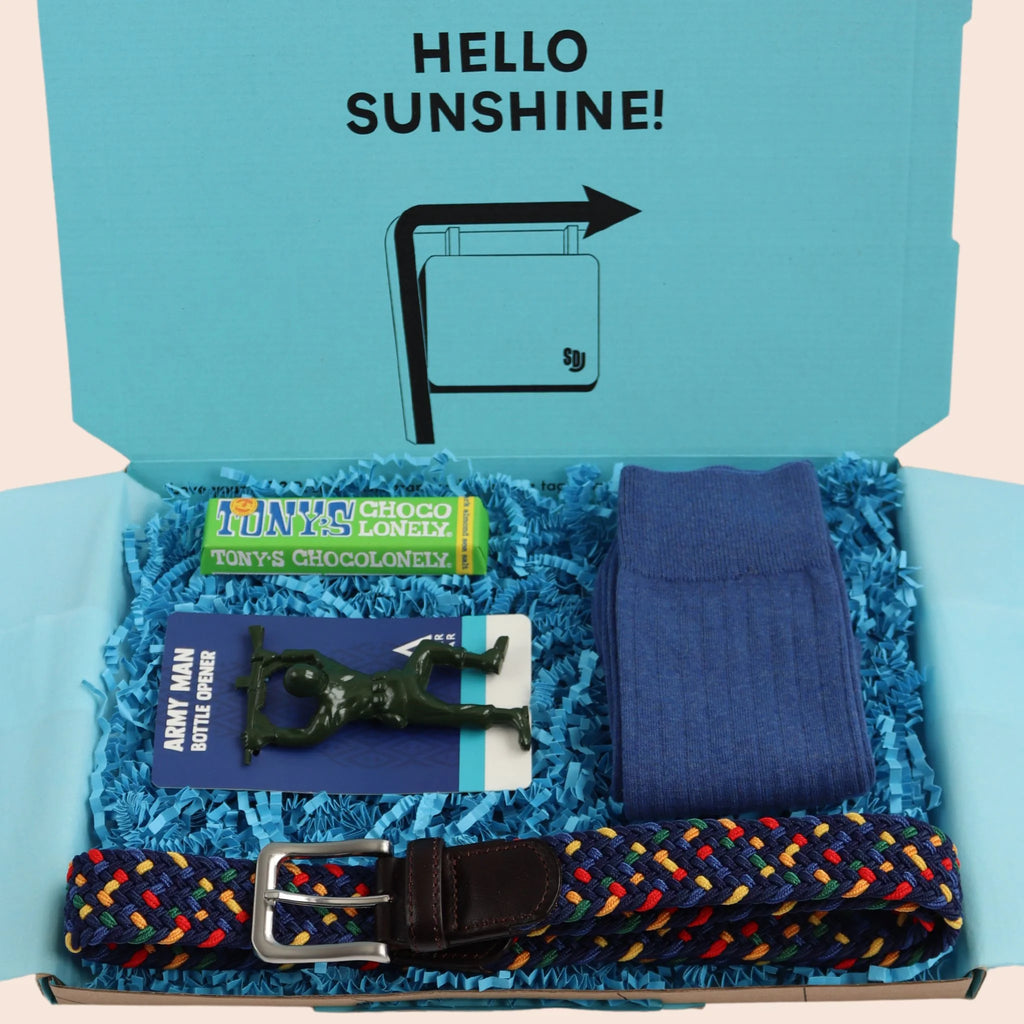 turquoise gift box with the words hello sunshine. The box contains Tonys chocolate, army man bottle opener, multi coloured woven elastic belt,  and blue socks.The packaging is plastic free with turquoise tissue with turquoise paper shred