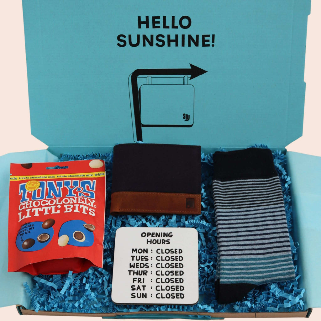 turquoise gift box with the words hello sunshine. The box contains Tonys chocolate, blue canvas and leather wallet, coaster with opening hours mon to sun closed, and blue stripe socks. The packaging is plastic free with turquoise tissue with turquoise paper shred